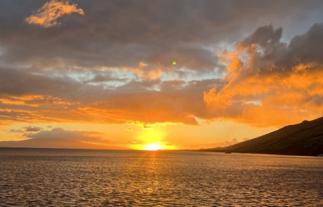 A beautiful sunset with yellows, oranges and grays in the sky. The sun is reflecting off the water.