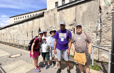 Travelers standing in front of a piece of the Berlin Wall