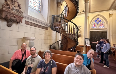 Travelers in the Loretto Chapel with the Miraculous stairway behind them