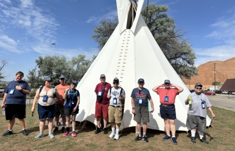 The travelers are standing in front of a teepee