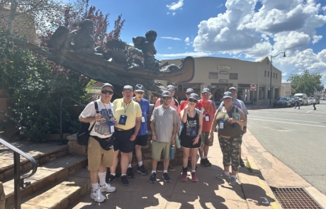 The group is walking around Santa Fe, they are standing in front of some art work.