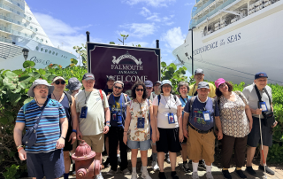Travelers in front of the Historic Falmouth Jamaica Welcome sign.