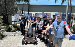 Travelers by a historical cannon at the Fort George site.