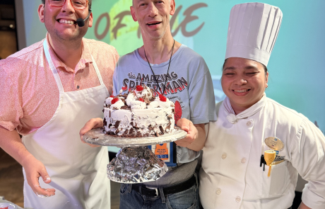 Traveler with cruise director and chef Mama during a cake battle